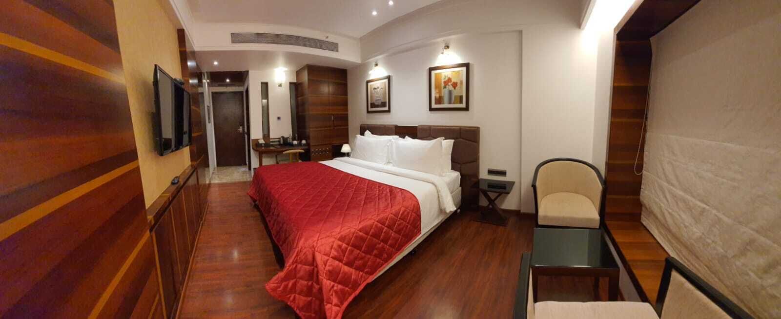 Une chambre d’hôtel avec un grand lit, un bureau, une chaise et un téléviseur.