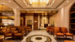 A lobby with a large chandelier, marble flooring, and leather seating. - Hotel MBC Citadel Nashik (Nashik)