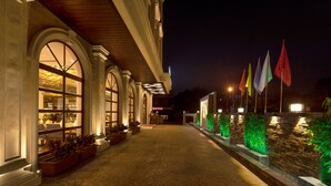 A hotel corridor with arched windows, a stone pathway, and a row of flags. - Hotel MBC Citadel Nashik (Nashik)