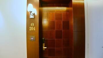 Un ascenseur avec un revêtement en bois, un écran numérique et le numéro 204 sur la porte.
