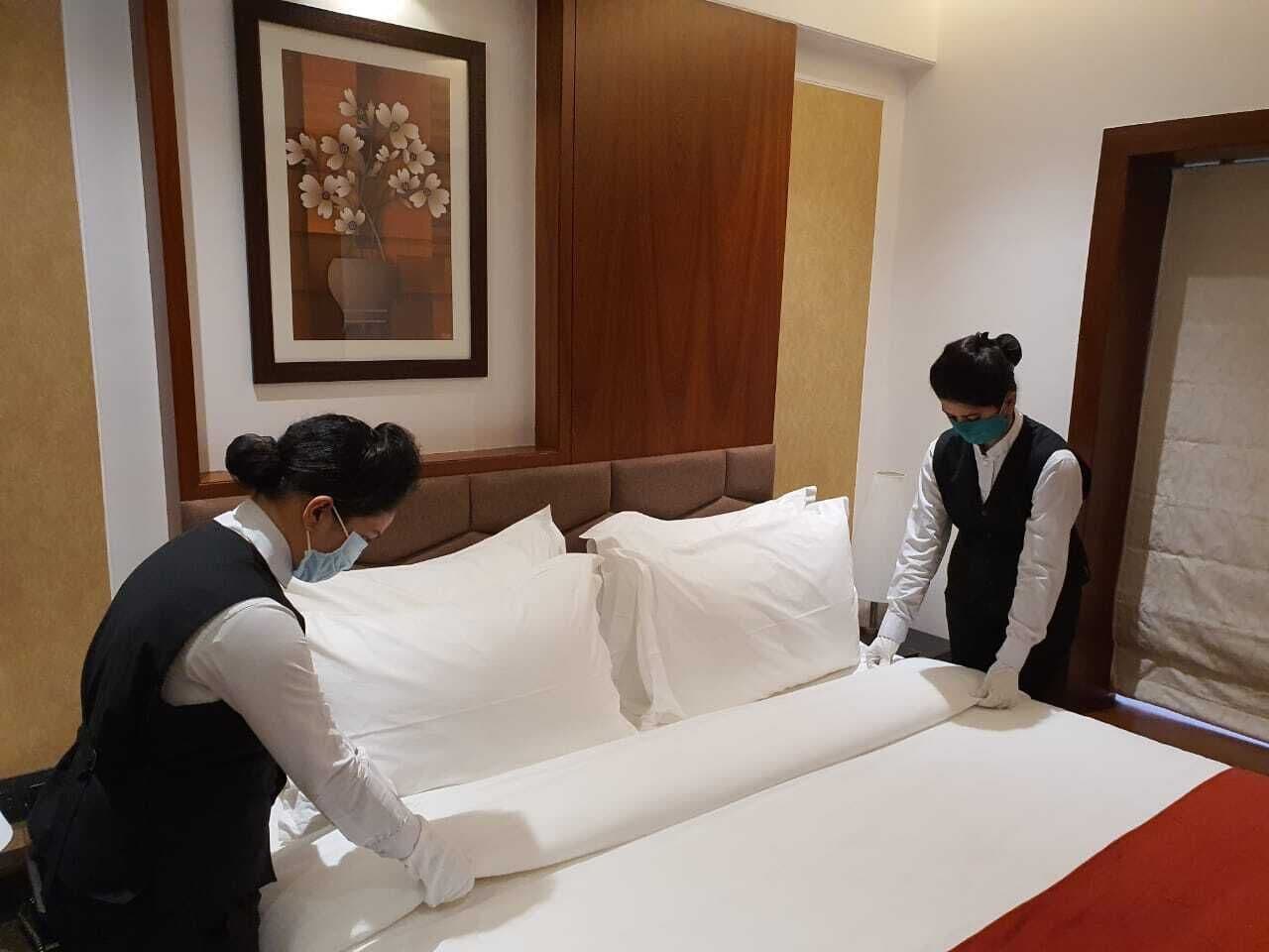 Una habitación de hotel con una cama bien hecha, una obra de arte floral enmarcada en la pared y un cabecero de madera.