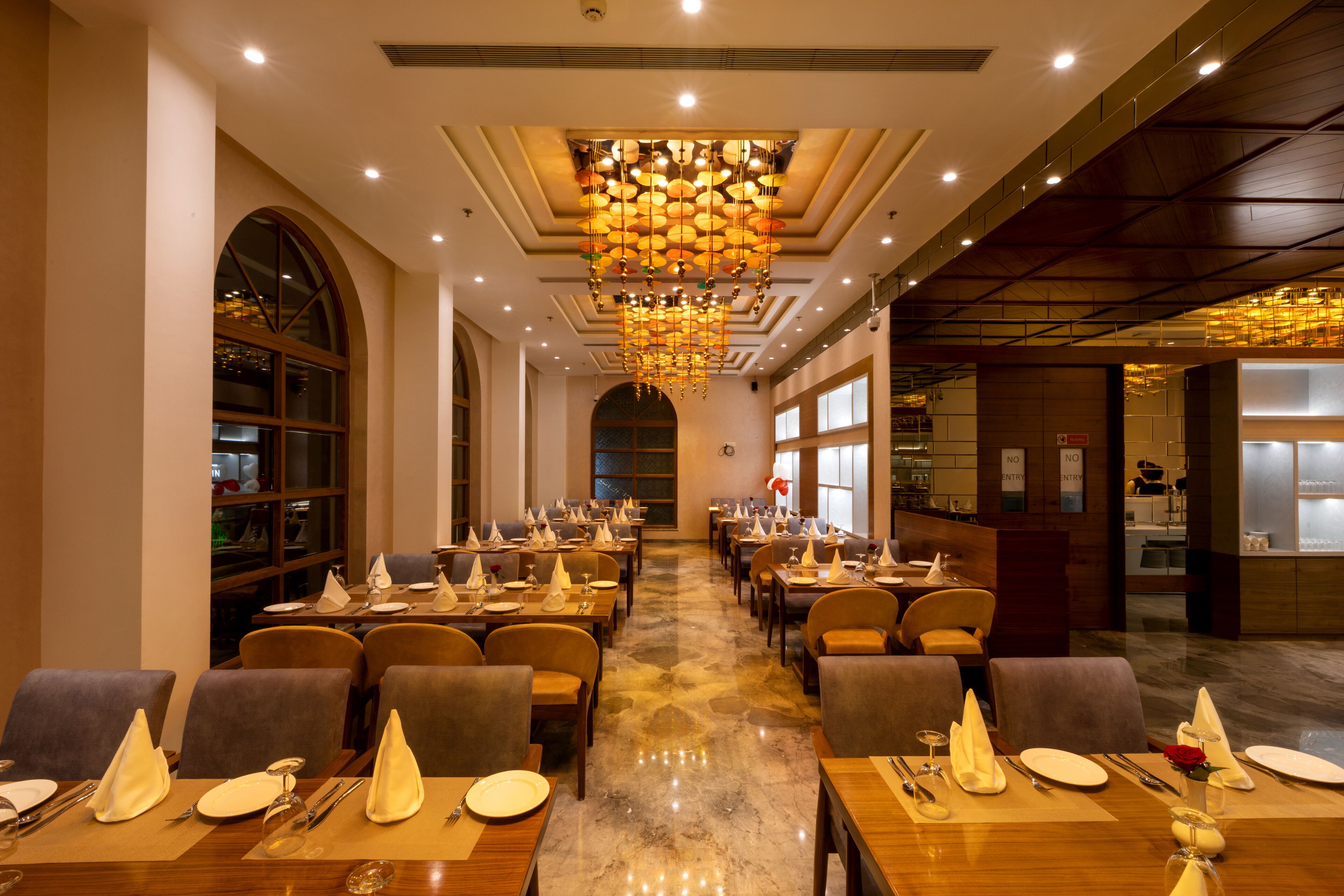 Un restaurante espacioso con varias mesas, sillas y un candelabro central.