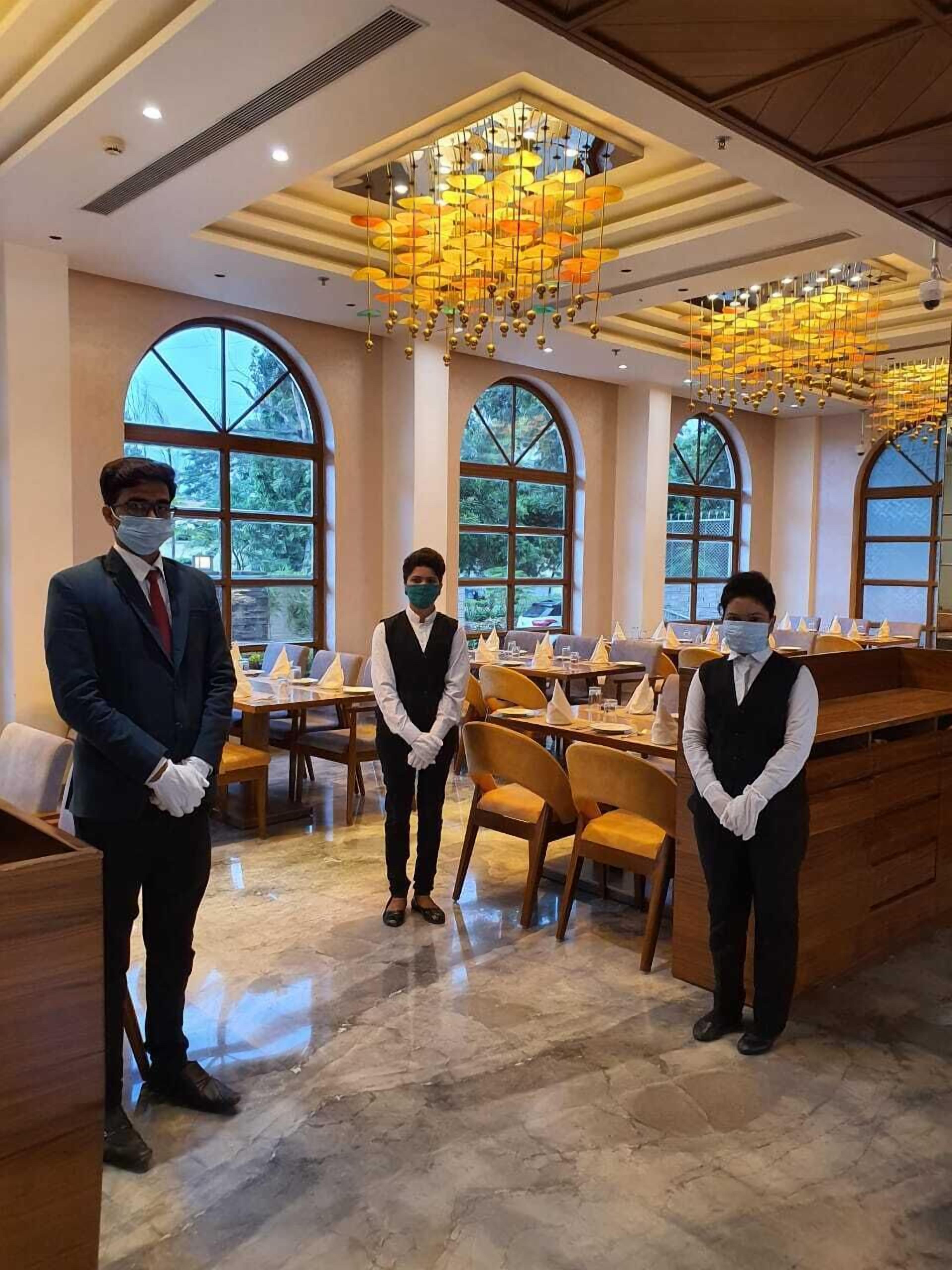 A restaurant with a high ceiling, large windows, and a chandelier.