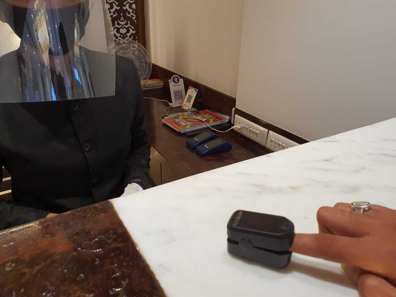 A hotel reception desk with a marble counter, a black coat hanging, a fan, and a QR code on a card.