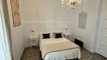 Un dormitorio con una cama grande, una araña, un espejo y suelo estampado.