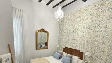 Une chambre à coucher comprenant un lit, une table de chevet, une chaise, une table, un miroir et un lustre.