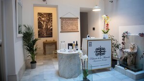 Een receptie met een marmeren balie, ingelijste kunstwerken, potplanten en een decoratieve orchidee-arrangement.
