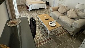 Een hotelkamer met een bed, een bank, een kleine tafel, een kroonluchter en een vloer met een patroon.