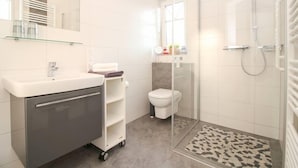 Une salle de bain moderne avec une douche à parois de verre, un lavabo blanc et des toilettes.