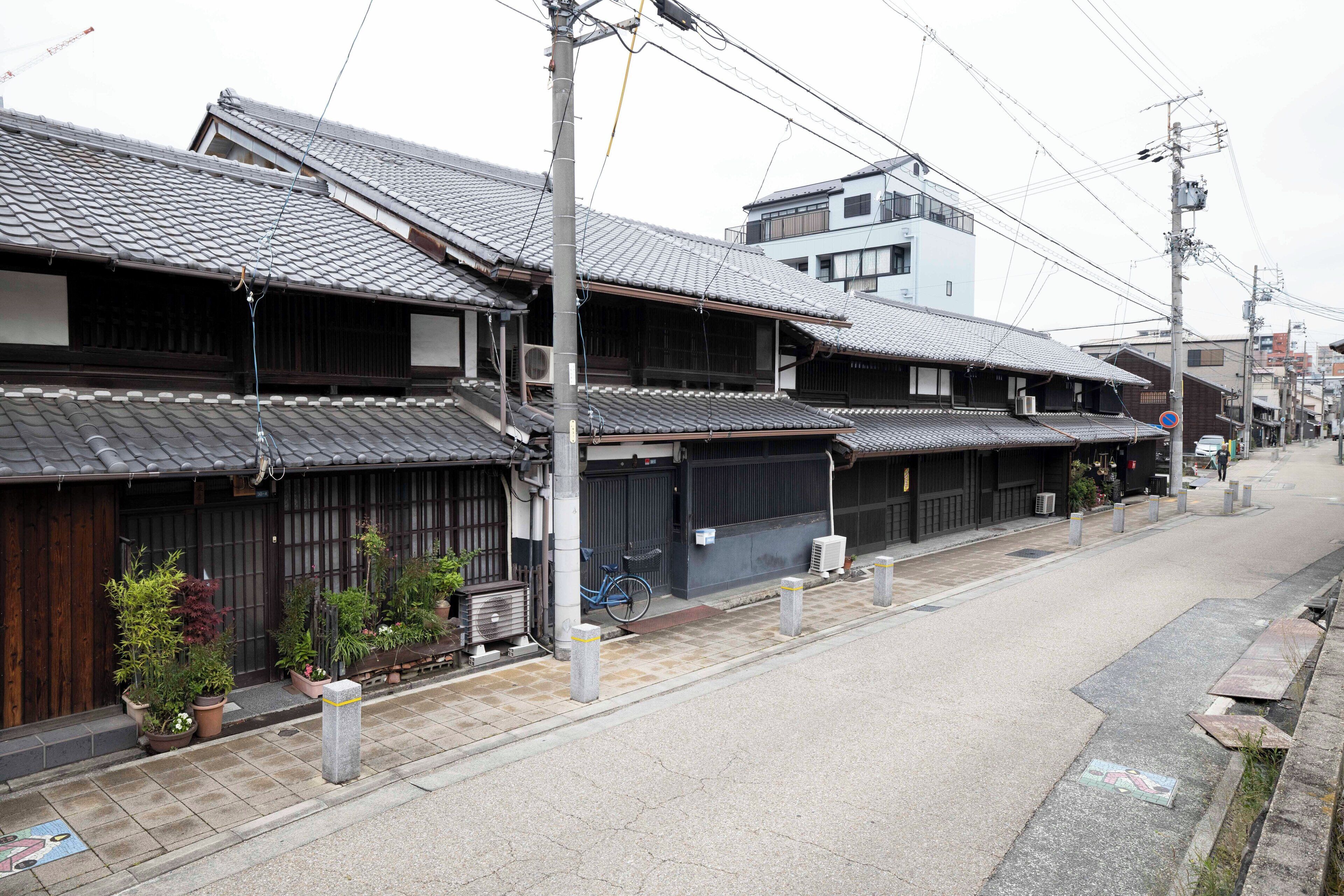 A traditional Japanese street with wooden buildings, a bicycle, and potted plants.