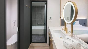 A modern bathroom with a bathtub, a large mirror, and two towels labeled "nikko Style".