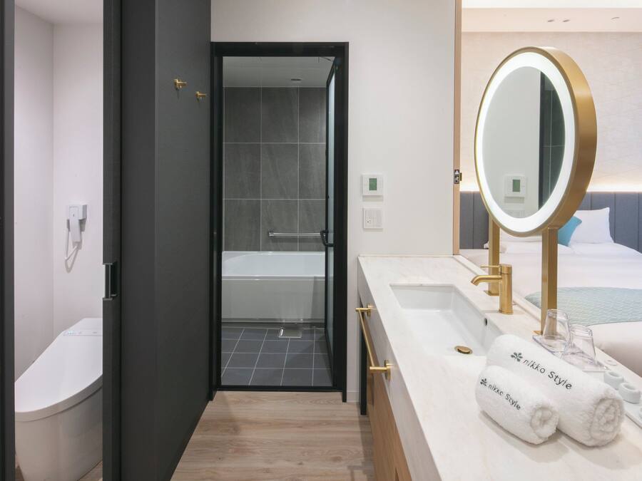 A modern bathroom with a bathtub, a large mirror, and two towels labeled "nikko Style".