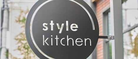A circular sign with the words "style kitchen" hanging from a metal structure.