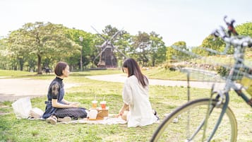 Two people sitting on a blanket in a park with a windmill in the background.