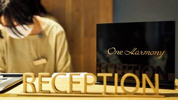 A reception desk with a laptop and wooden letters spelling "RECEPTION" and a sign that reads "One Harmony".