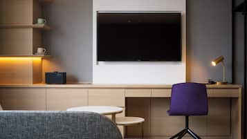 A modern living room with a large flat-screen TV mounted on the wall, a purple chair, a small round table, and a coffee table.
