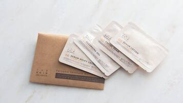 Una bolsa de papel marrón con la etiqueta "The Skin Delights" contiene cuatro paquetes de productos para el cuidado de la piel etiquetados como "Serum Lotion" y "Serum Milky Lotion" sobre una superficie de mármol.