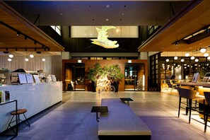 Ein modernes Interieur mit einer Rezeption, einer Sitzecke und einer großen Topfpflanze.