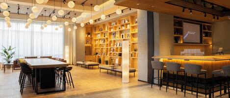 Un moderno vestíbulo de hotel con un amplio mostrador de recepción de madera, zonas de estar cómodas y una estantería bien organizada.