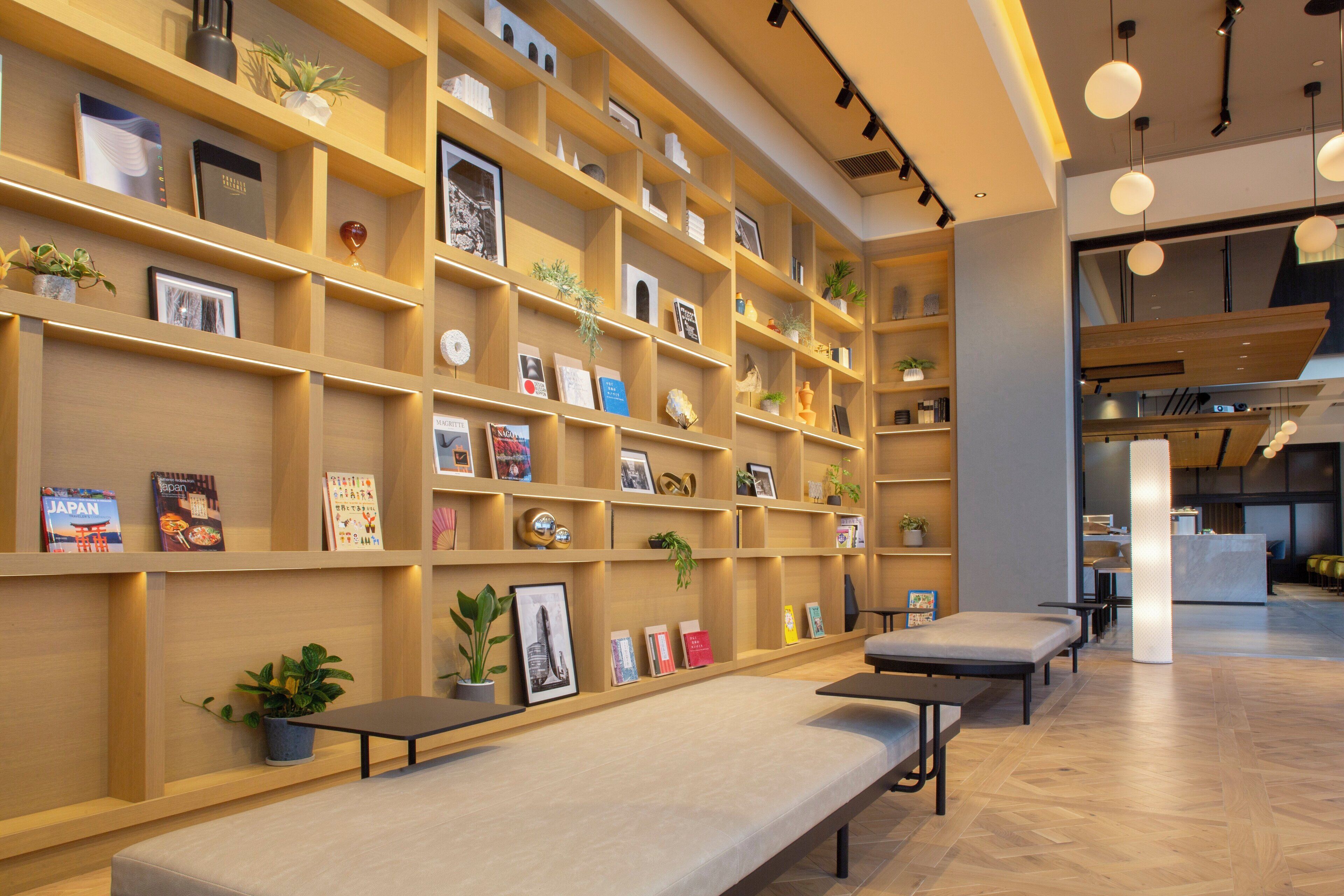 A modern interior with wooden shelving filled with books and decorative items, a seating area with benches, and a reception desk.