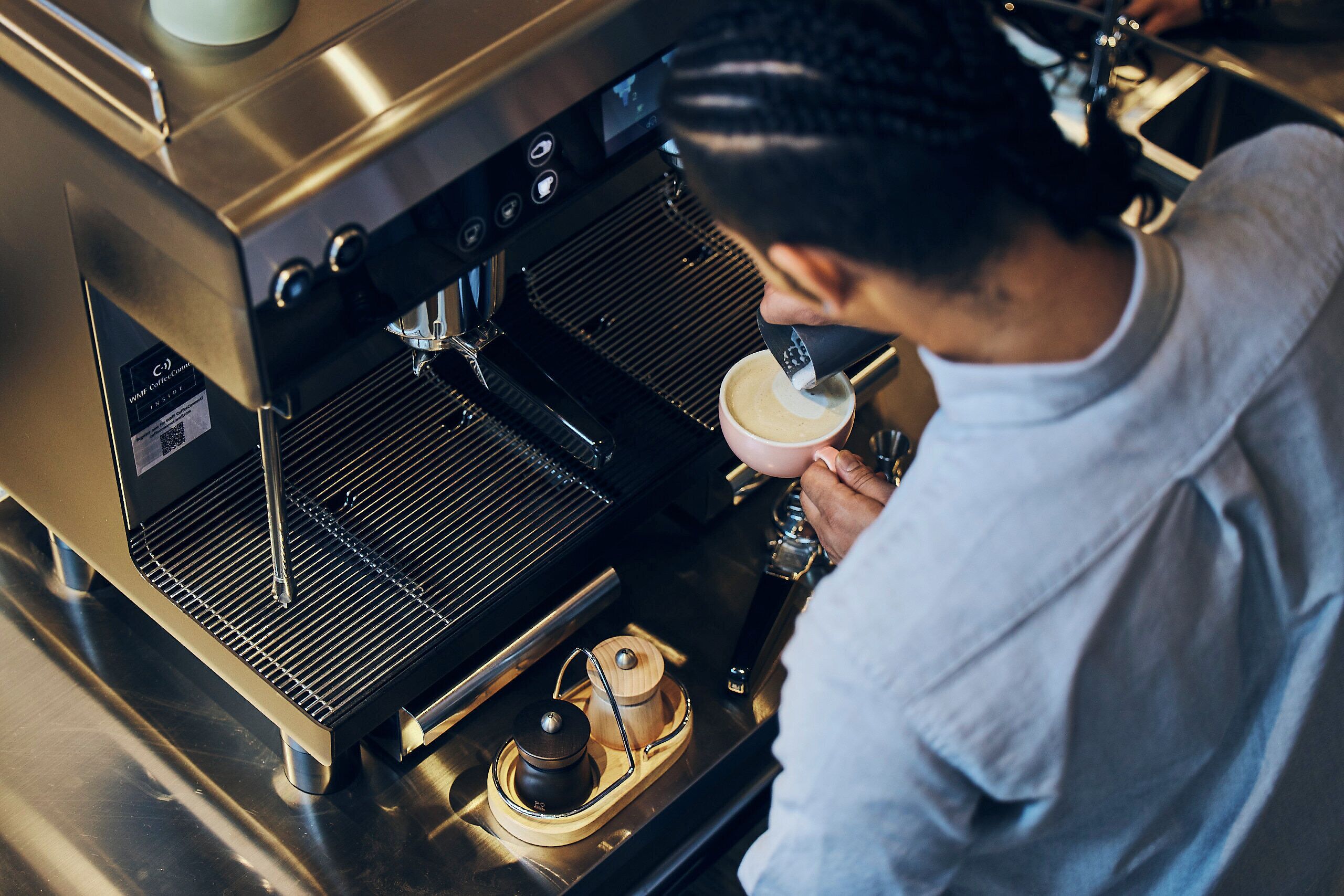 A person operating a coffee machine, likely in a cafe or restaurant setting.