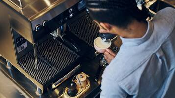 Une personne qui utilise une machine à café, probablement dans un café ou un restaurant.