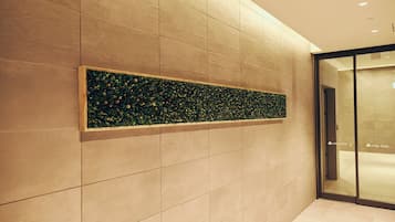 A modern interior with a tiled wall and a decorative panel with green foliage.