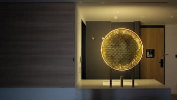 A modern bathroom with a circular light fixture and a wooden door in the background.