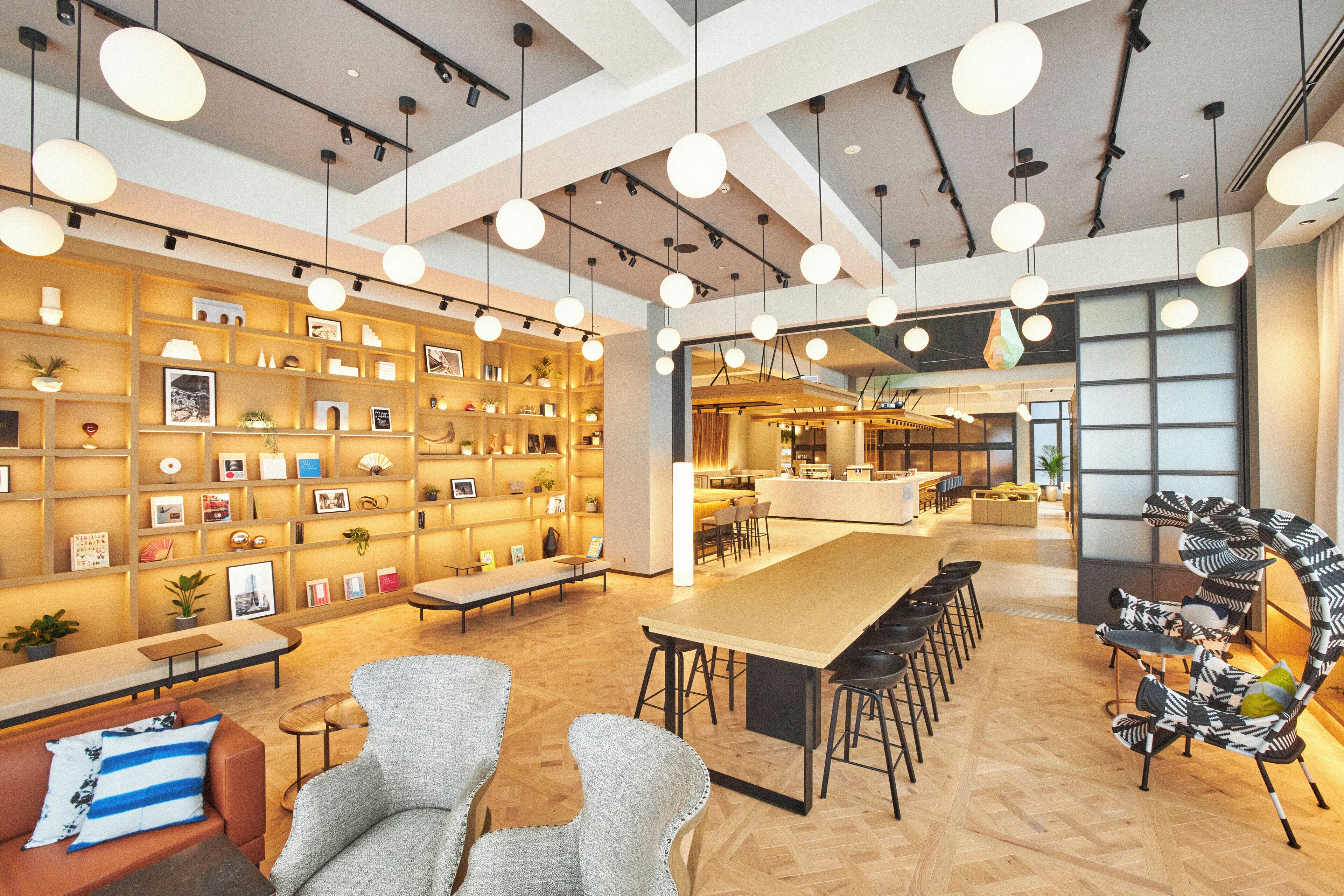 A modern interior with a long communal table, several bar stools, and a unique zebra-striped chair.