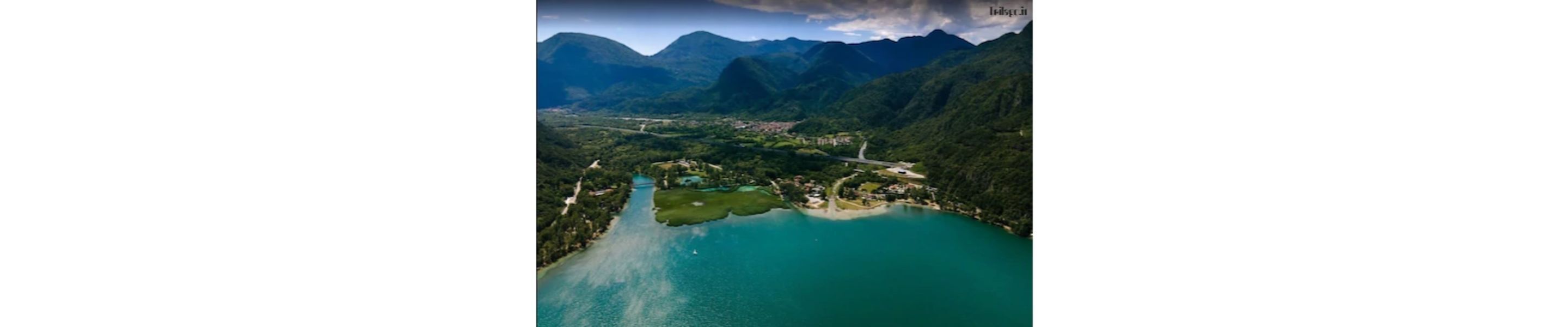Vista aérea de una zona costera con un lago turquesa, rodeado de colinas y montañas verdes y frondosas.