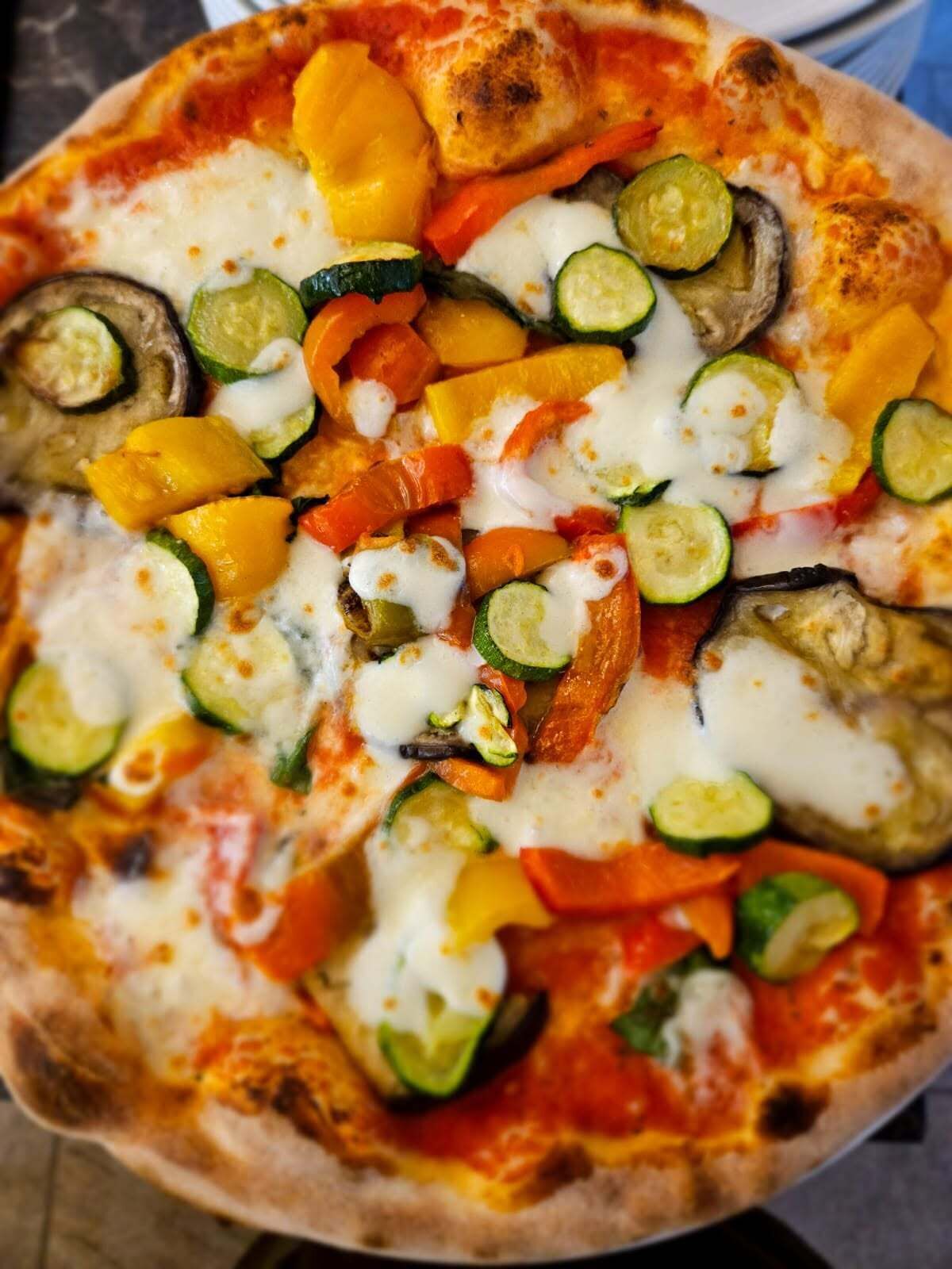 Una pizza con verduras y queso sobre una superficie plana.