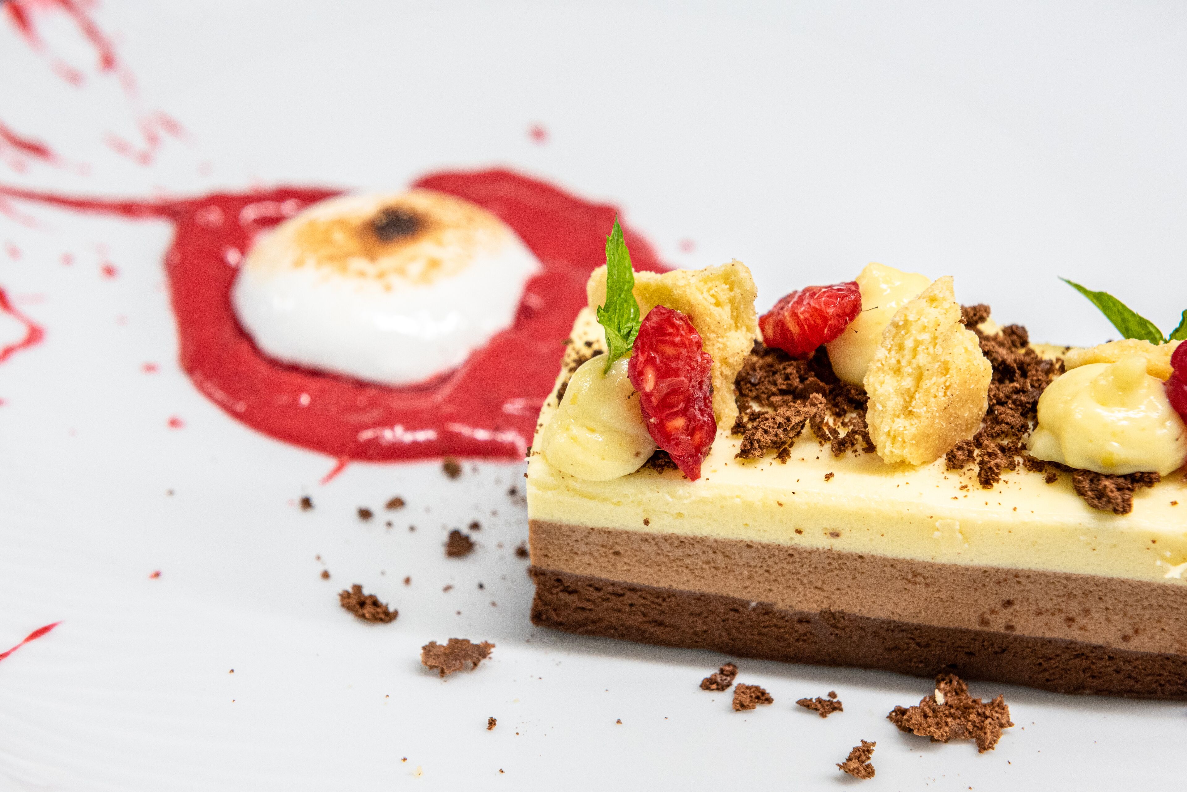 Un dessert composé d’un gâteau à plusieurs couches, de fraises et d’une quenelle de crème.