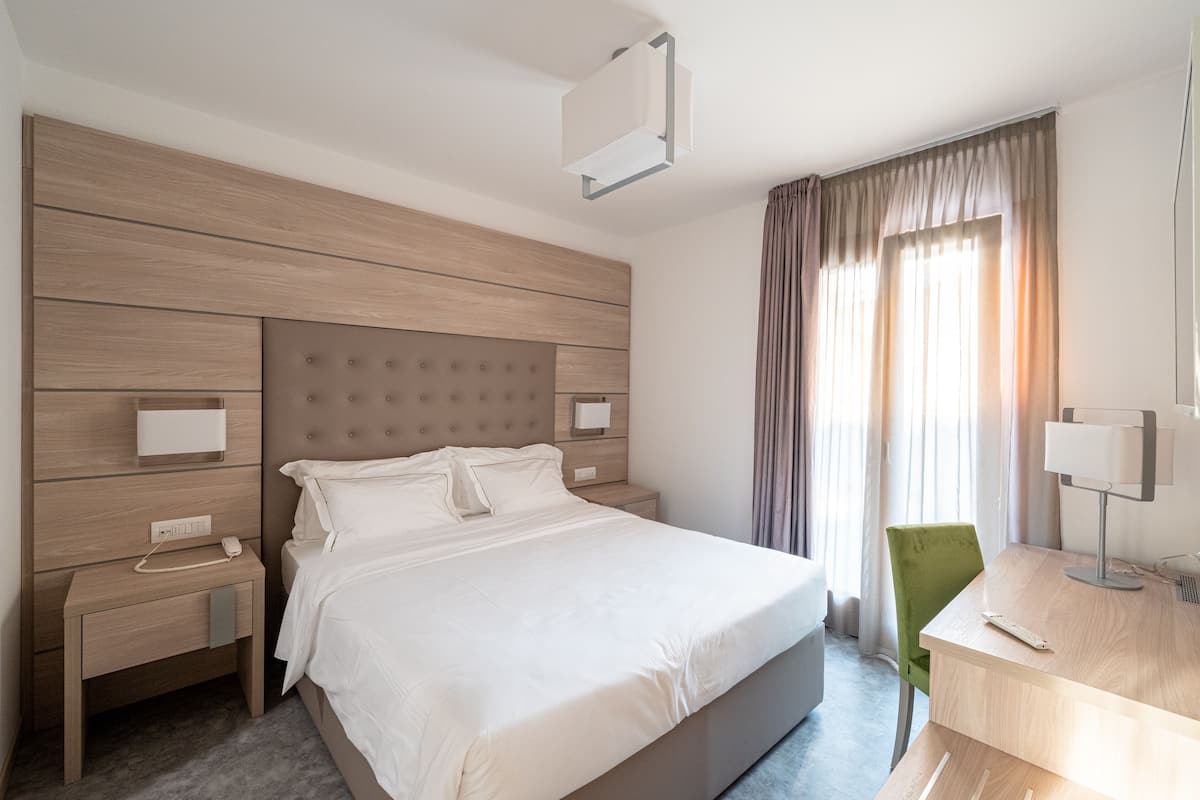 A modern hotel room with a large bed, a desk, and a chair.