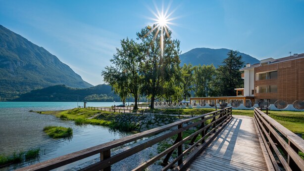 Un muelle de madera que lleva a un edificio con vistas a un lago y montañas.