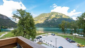 Un estacionamiento con autos, un lago y montañas al fondo.