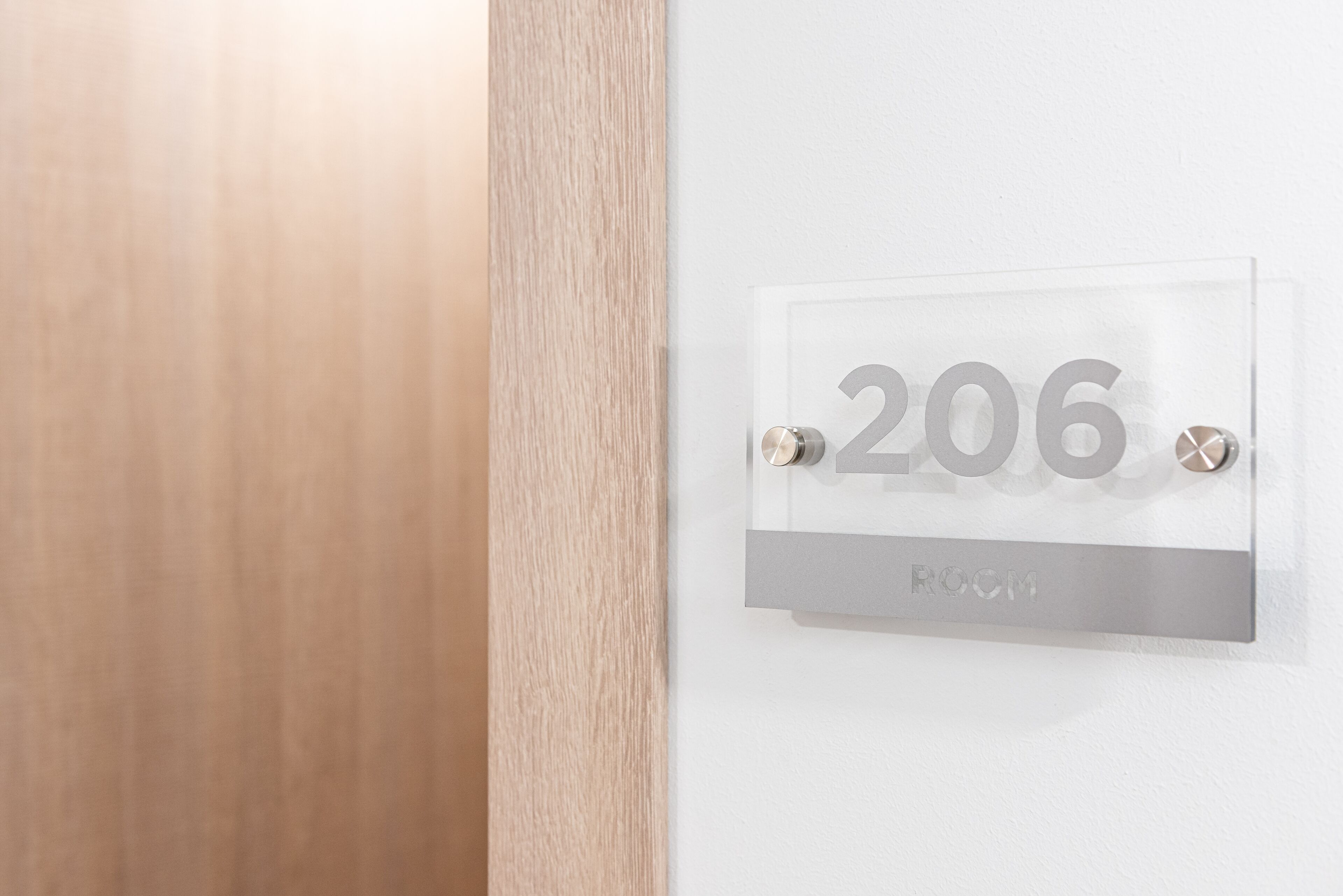 A clear room number sign with the number 206 and the word "ROOM" below it, indicating the room number.
