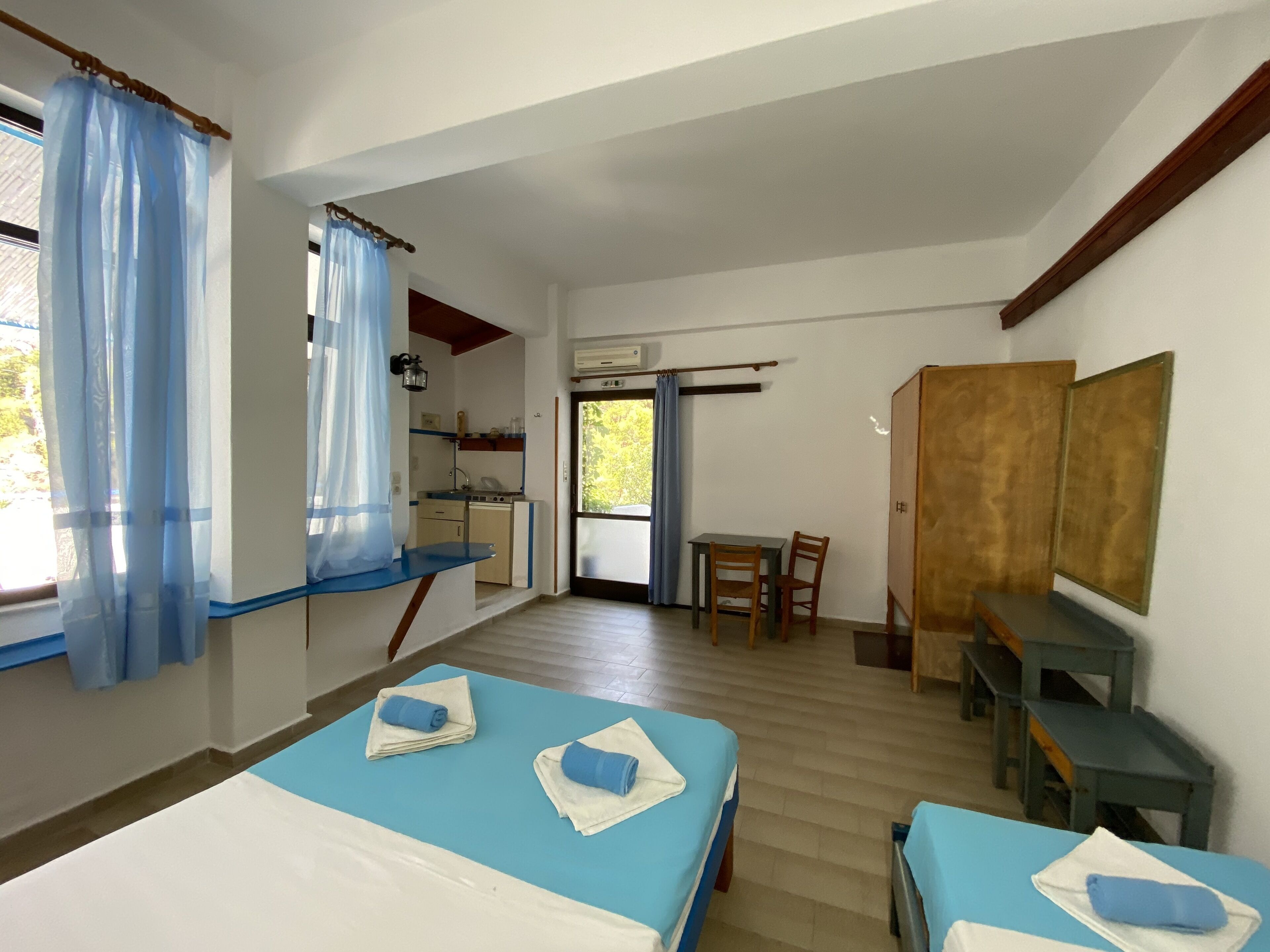 Een kamer met twee bedden, een klein kitchenette, een eethoek en een kledingkast.