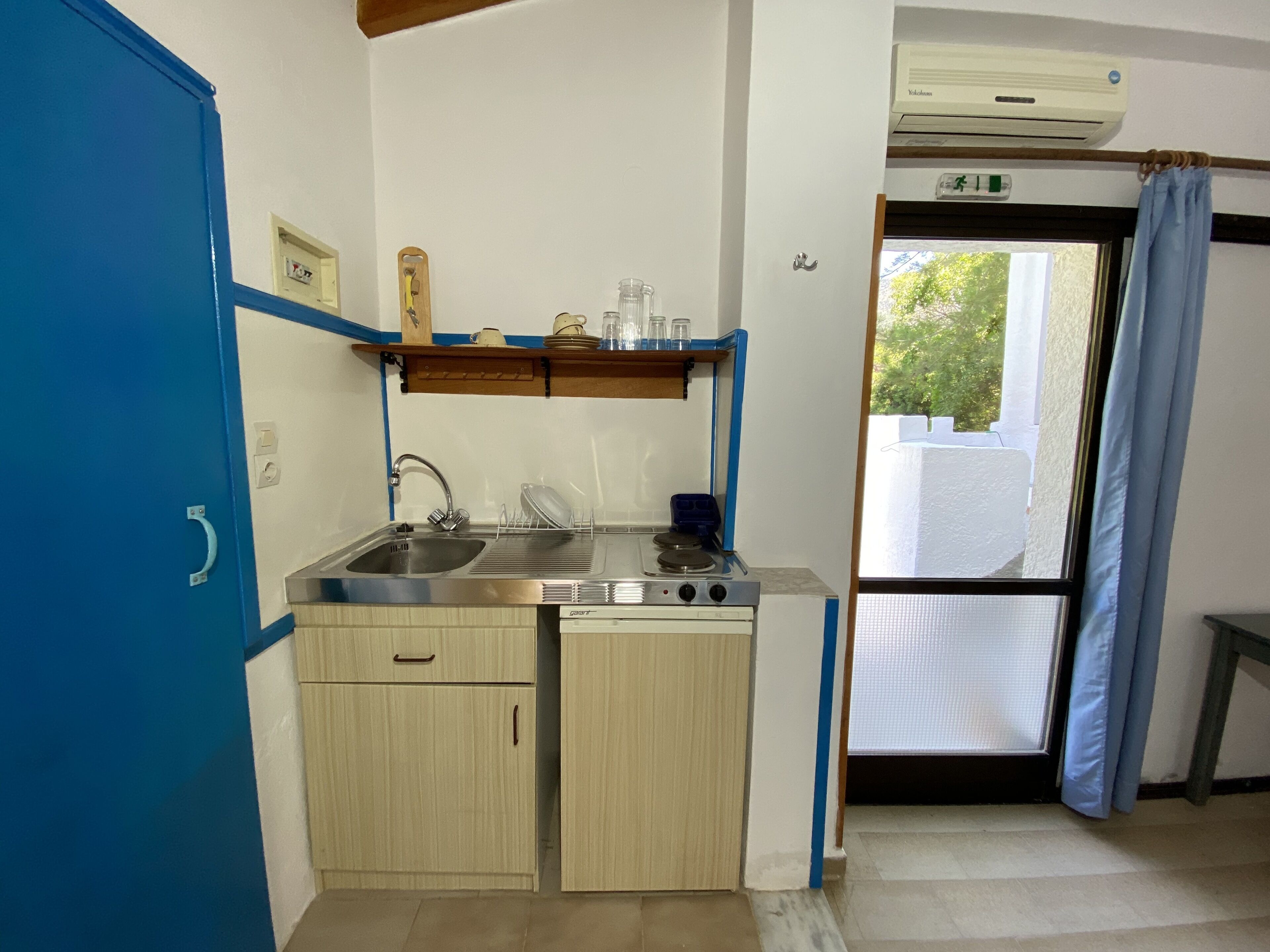 A compact kitchen with a sink, stove, and a small window.