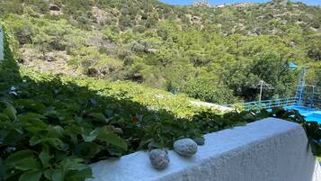A view of a mountainous landscape with dense greenery and a clear blue sky.