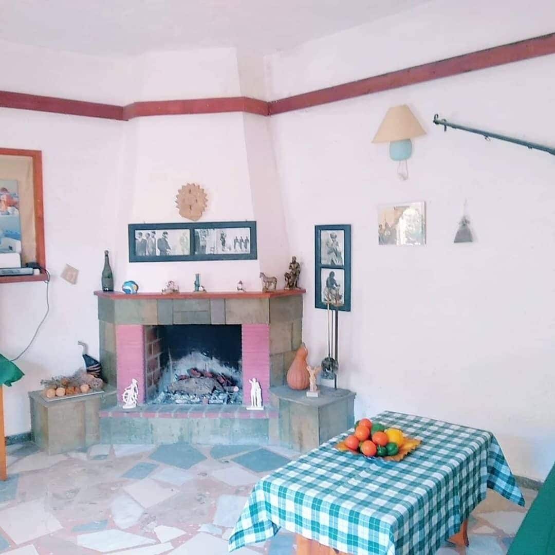 Una sala de estar con chimenea, una mesa a cuadros y diversas decoraciones en las paredes.