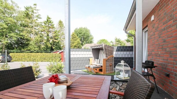 Un patio con una mesa de madera, dos tazas blancas y un comedero para pájaros.
