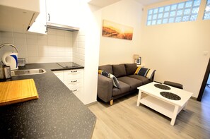 A compact living space with a kitchenette, a sofa, and a small dining table.