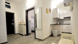 A modern kitchen with white cabinets, a countertop, and a trash bin. - Victus Apartamenty - Riviera (Sopot)