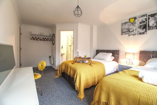 A hotel room with two beds, a desk, a chair, a shower, and a wall with a poster. - Modern city centre Apartment + free parking (Wakefield)