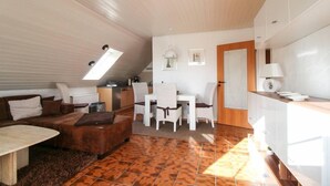 A modern interior with a dining area, sofa, and kitchen. - Muckelstuuv (Krummhoern)