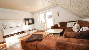 A modern living room with a brown leather sofa, white cabinets, and a flat-screen TV. - Muckelstuuv (Krummhoern)