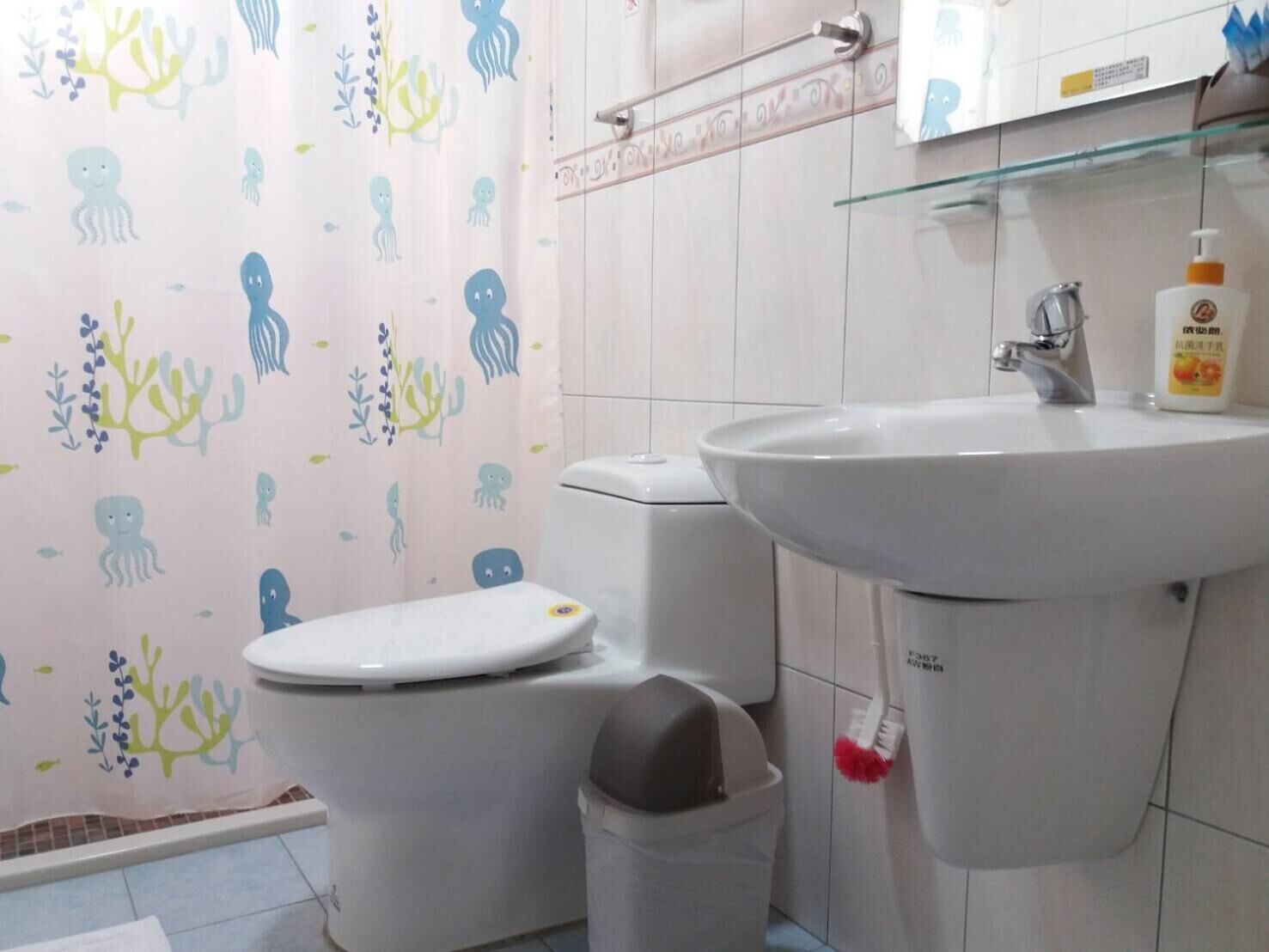 A bathroom with a toilet, sink, and a trash bin.