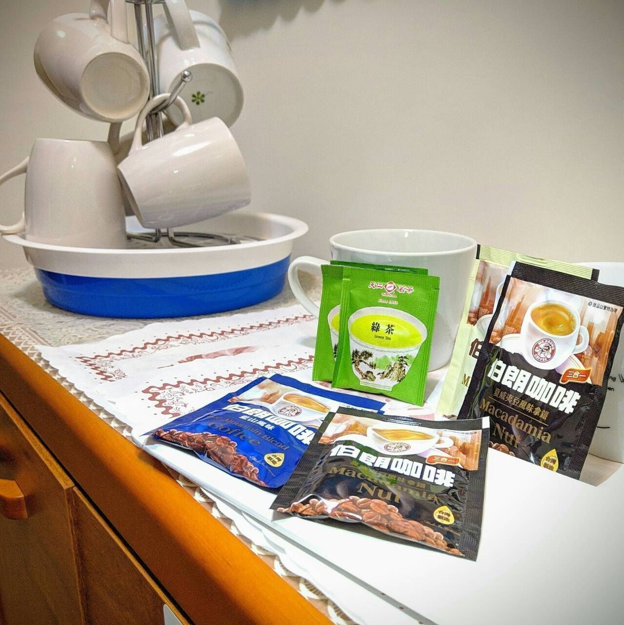 A table with a tea set, a white mug, and packets of tea and coffee.