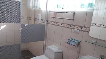 Un baño con inodoro, lavabo y zona de ducha.