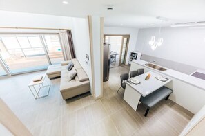 A modern, well-lit living area with a sofa, a dining table, and a kitchen area. - Nine to zero Pension (Hongcheon)